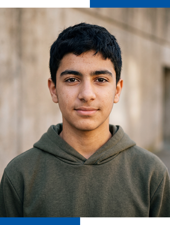 Un adolescent au regard calme esquisse un léger sourire devant un mur de ciment.